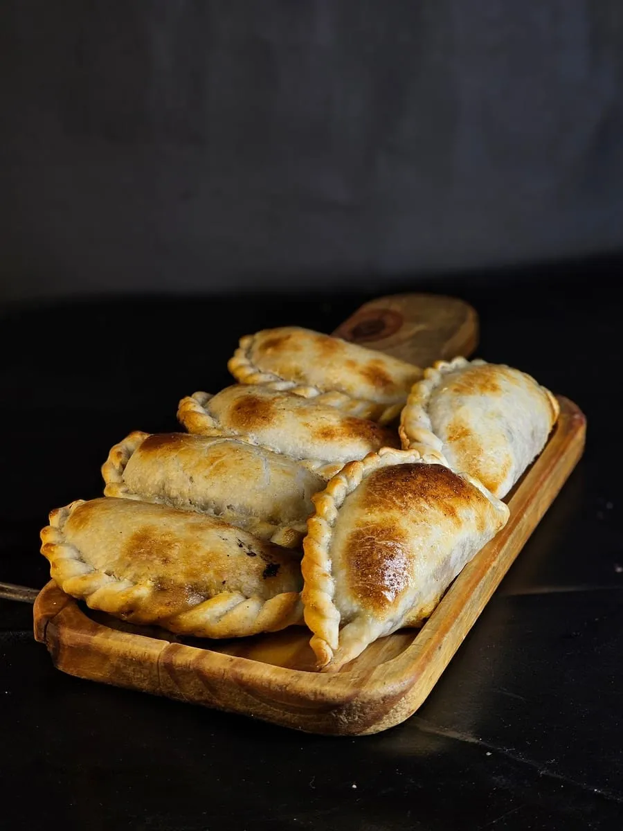 Empanadas doradas ordenadas en una bandeja de madera