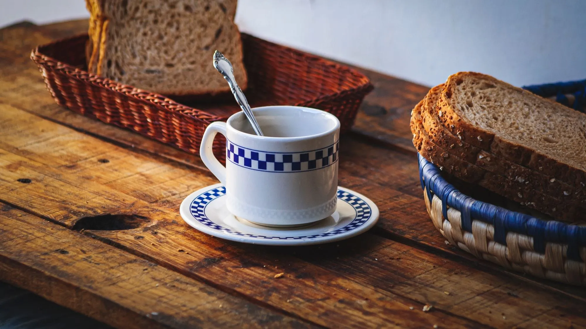 Canasta de pan y una taza de café sobre una mesa de madera