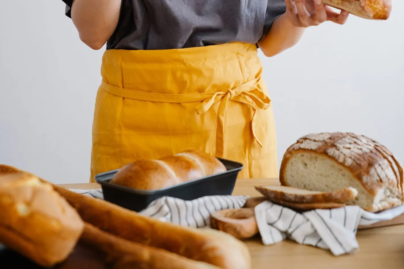 Panadera con mandil amarillo junto a los panes del día
